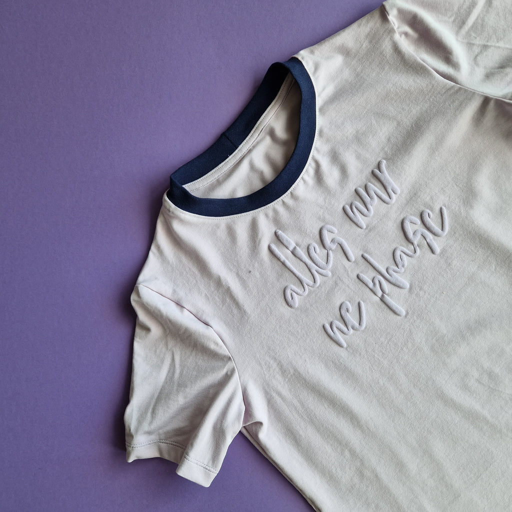 Light lilac t-shirt with blue trim and text on a purple background