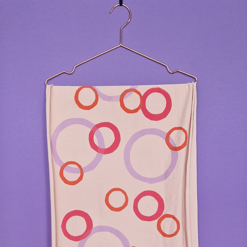 Fabric with circular bubble pattern on a hanger against a purple background