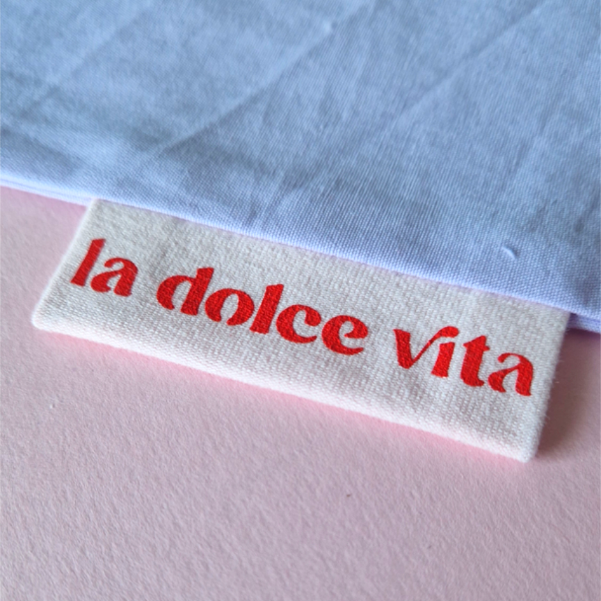 Label with 'la dolce vita' text on a light blue fabric background