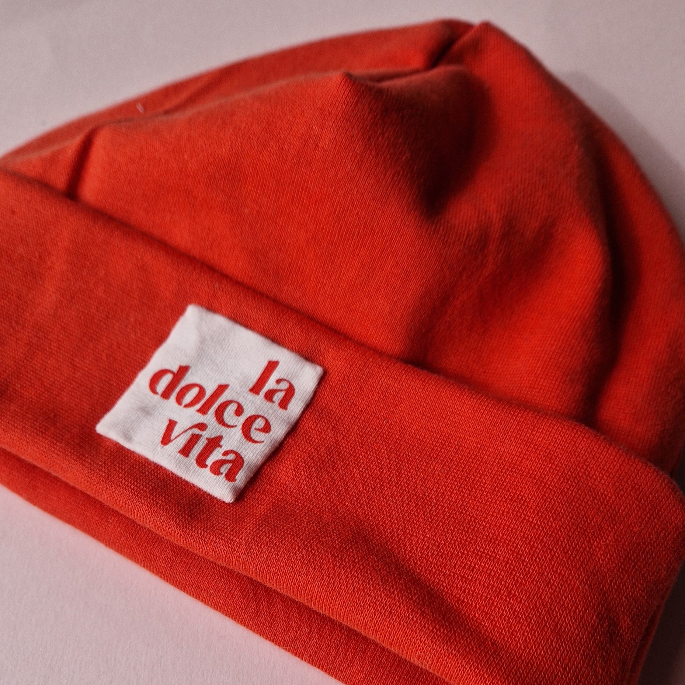 Red fabric with a creme rose label reading 'la dolce vita' on a light rose background