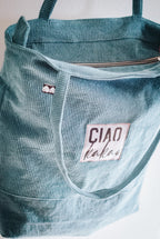 Green corduroy bag with a 'CIAO kakao' label on a white background