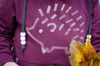 Purple hoodie with a hedgehog design on a sweater with autumn leaves.