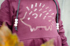 Purple hoodie with a hedgehog design and beads hanging from the hood.